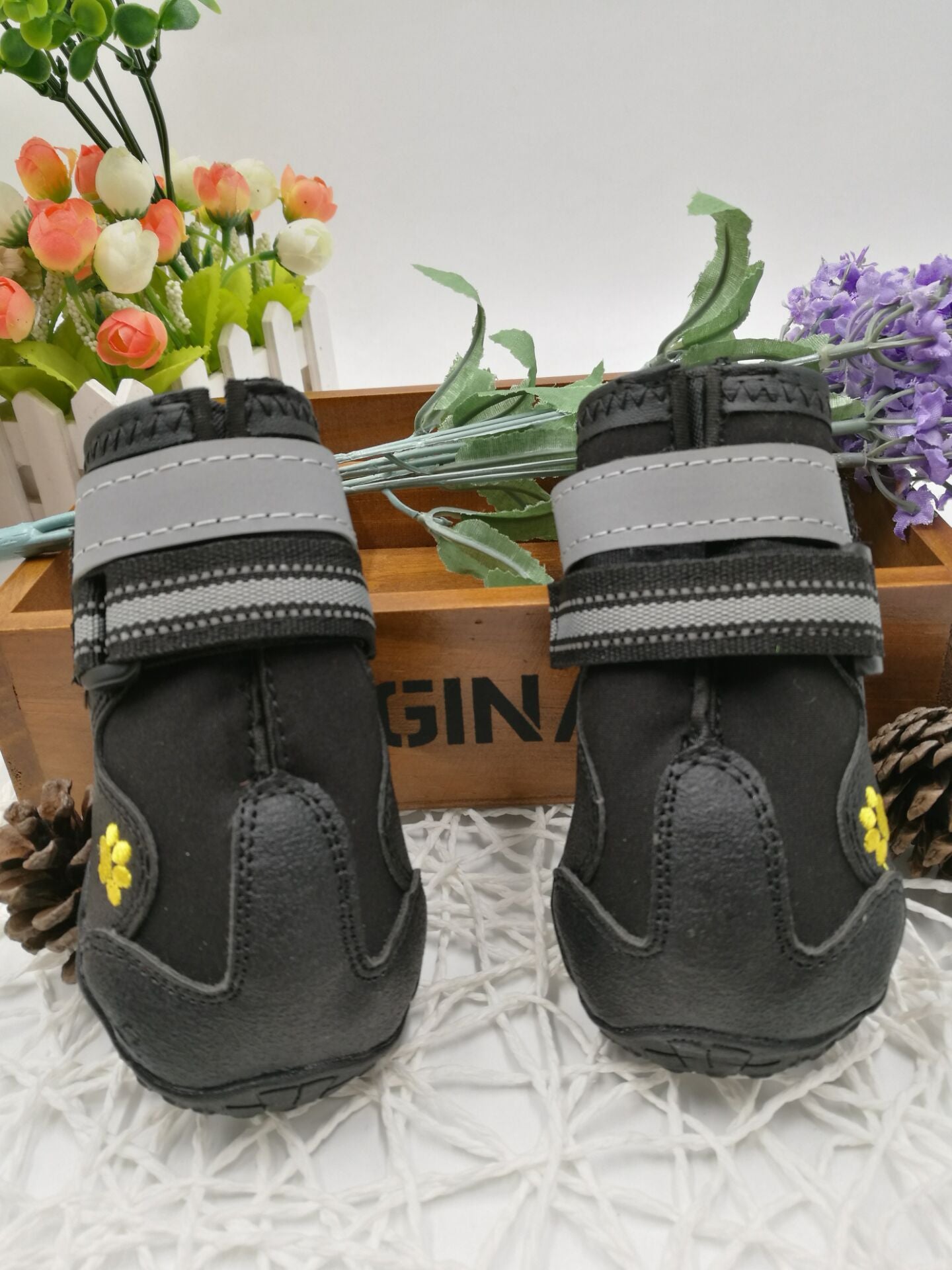 Pair of dog boots standing upright with reflective straps and paw logo visible.