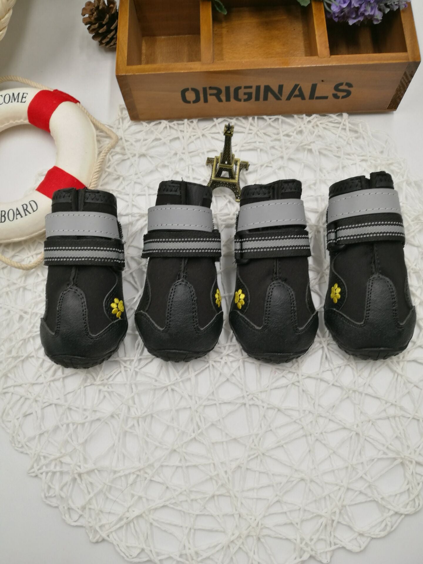 Set of four black waterproof dog boots with reflective straps, displayed together.