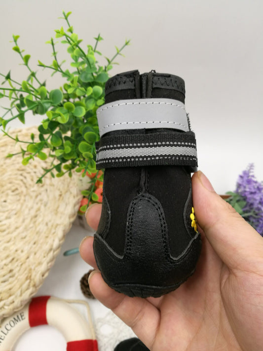 Black waterproof dog boot with reflective strap, shown being held upright.
